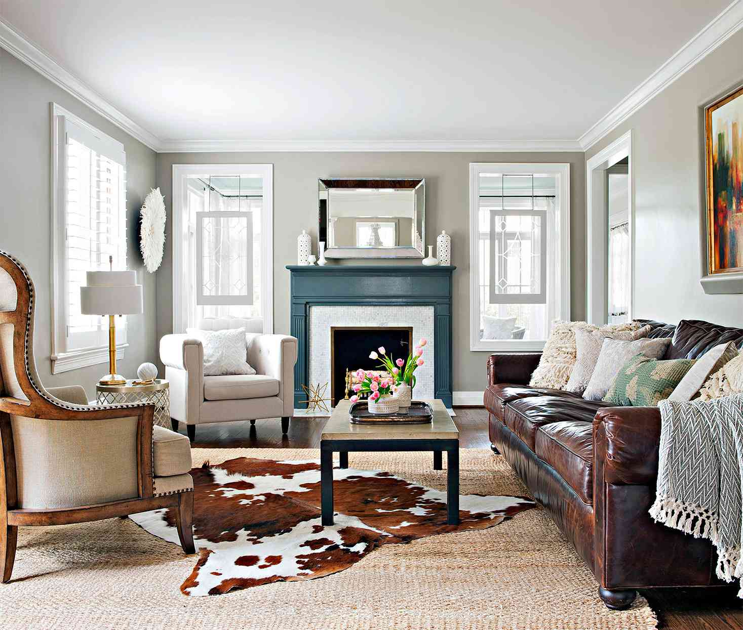 living room with neutral walls, teal painted mantel and cow-hide rug