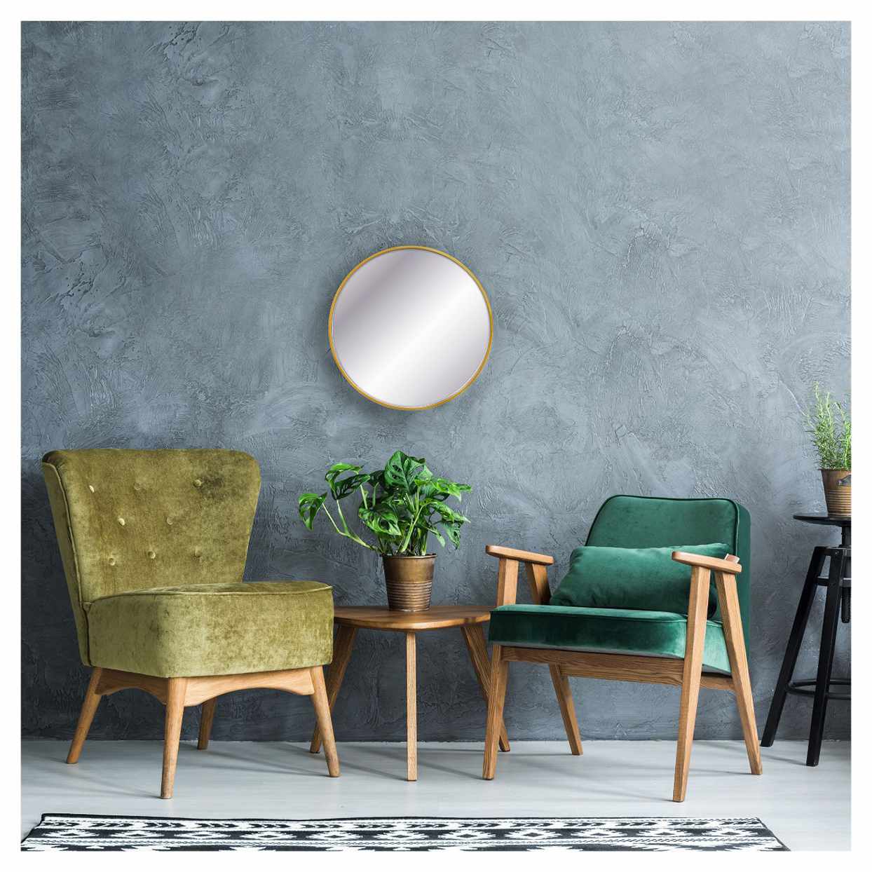 round gold mirror on wall above two green chairs and side table