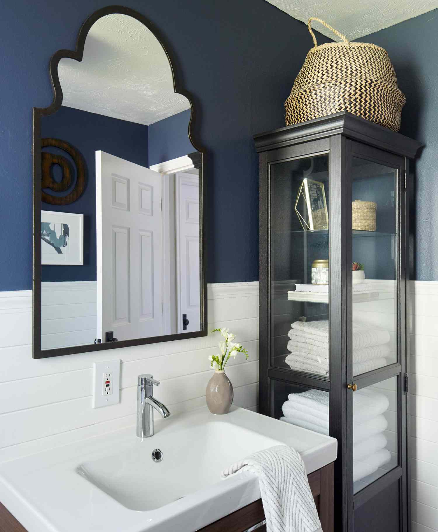 dark blue bathroom with tall black tower shelving holding towels