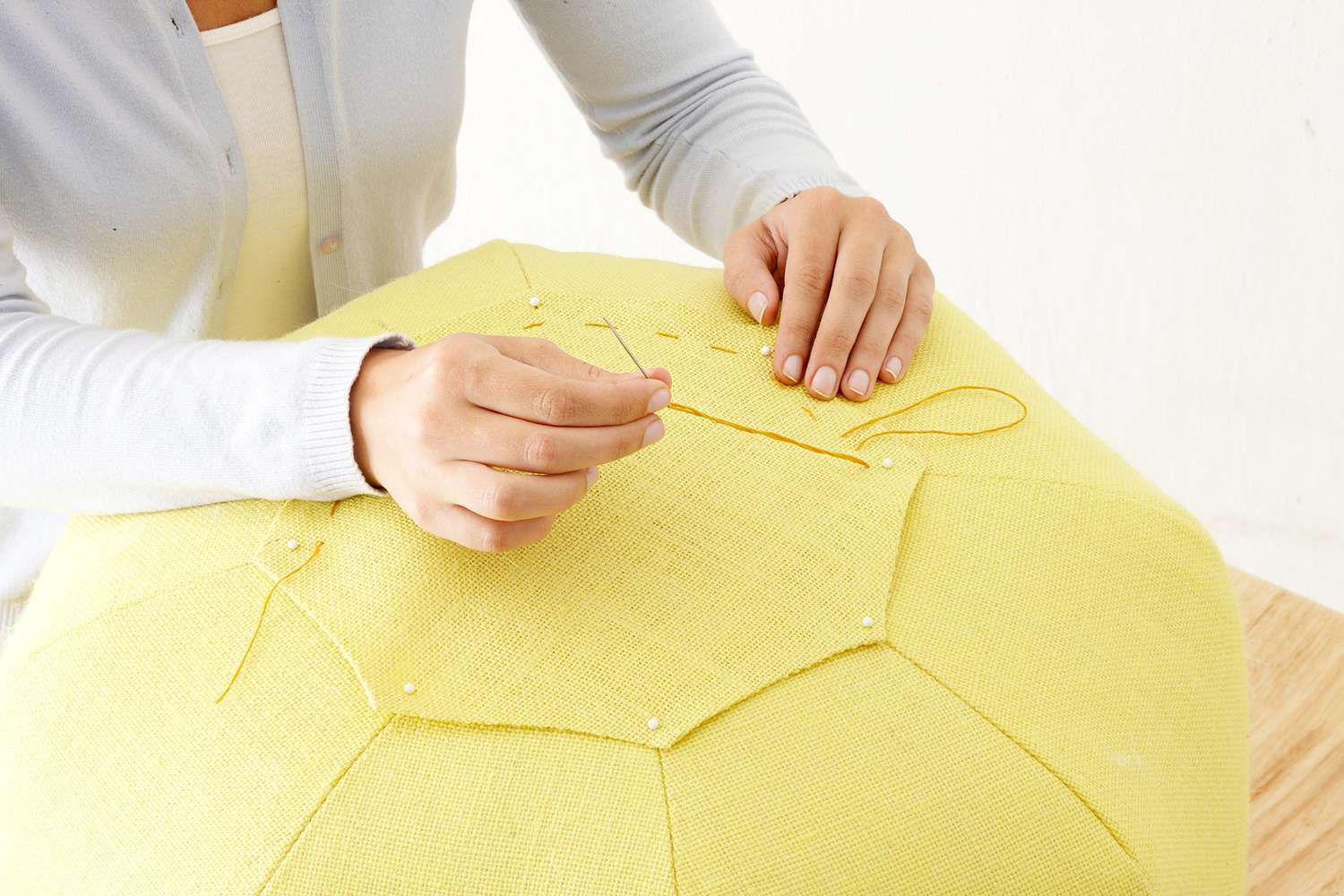 Person pinning octagon fabric onto pouf