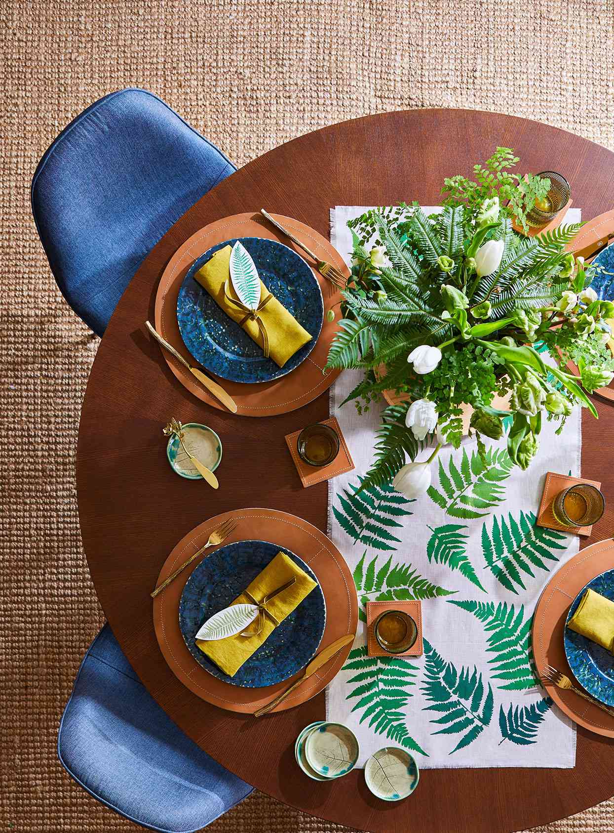 round wooden table with greenery place settings