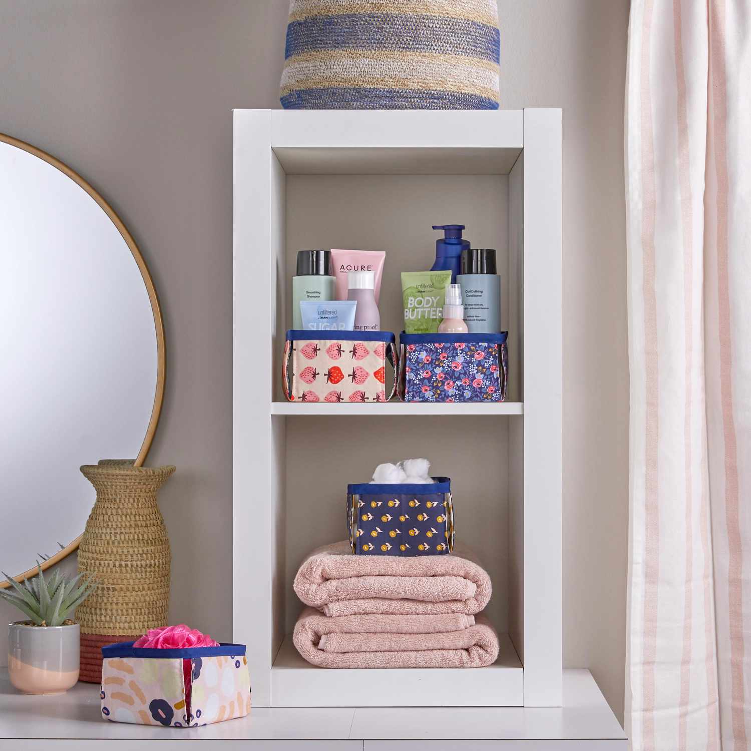 white bathroom cube shelves with fabric bins holding products