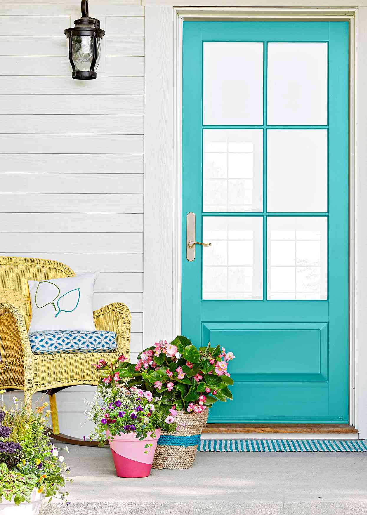 yellow wicker rocking chair next to turquoise front door exterior