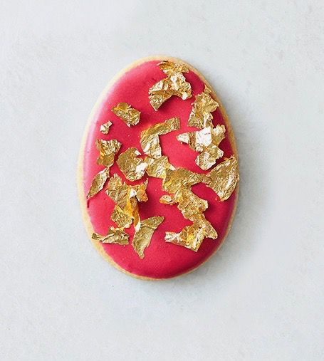egg shaped cookie with red frosting and edible gold leaf on top