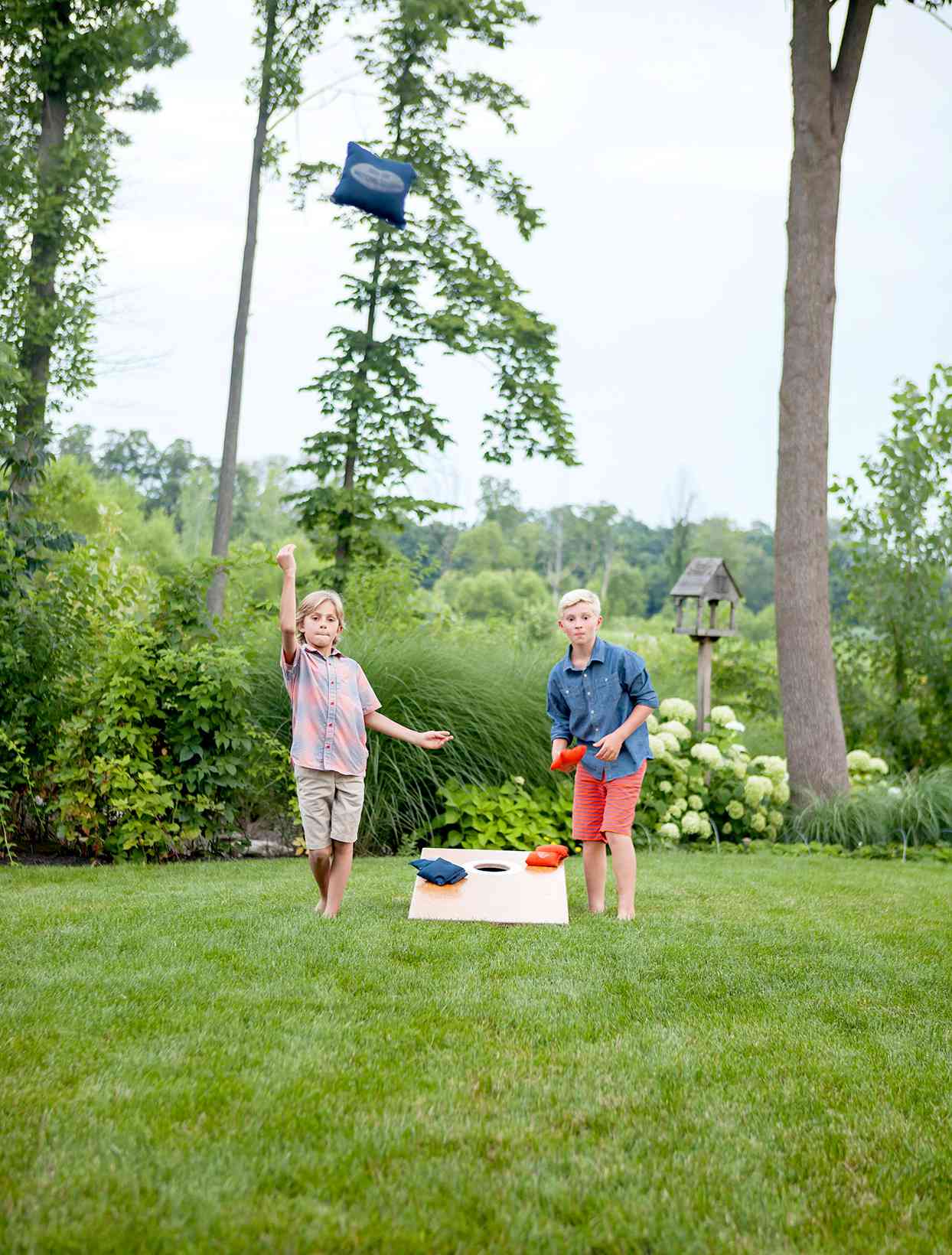 Two kids playing bags in yard