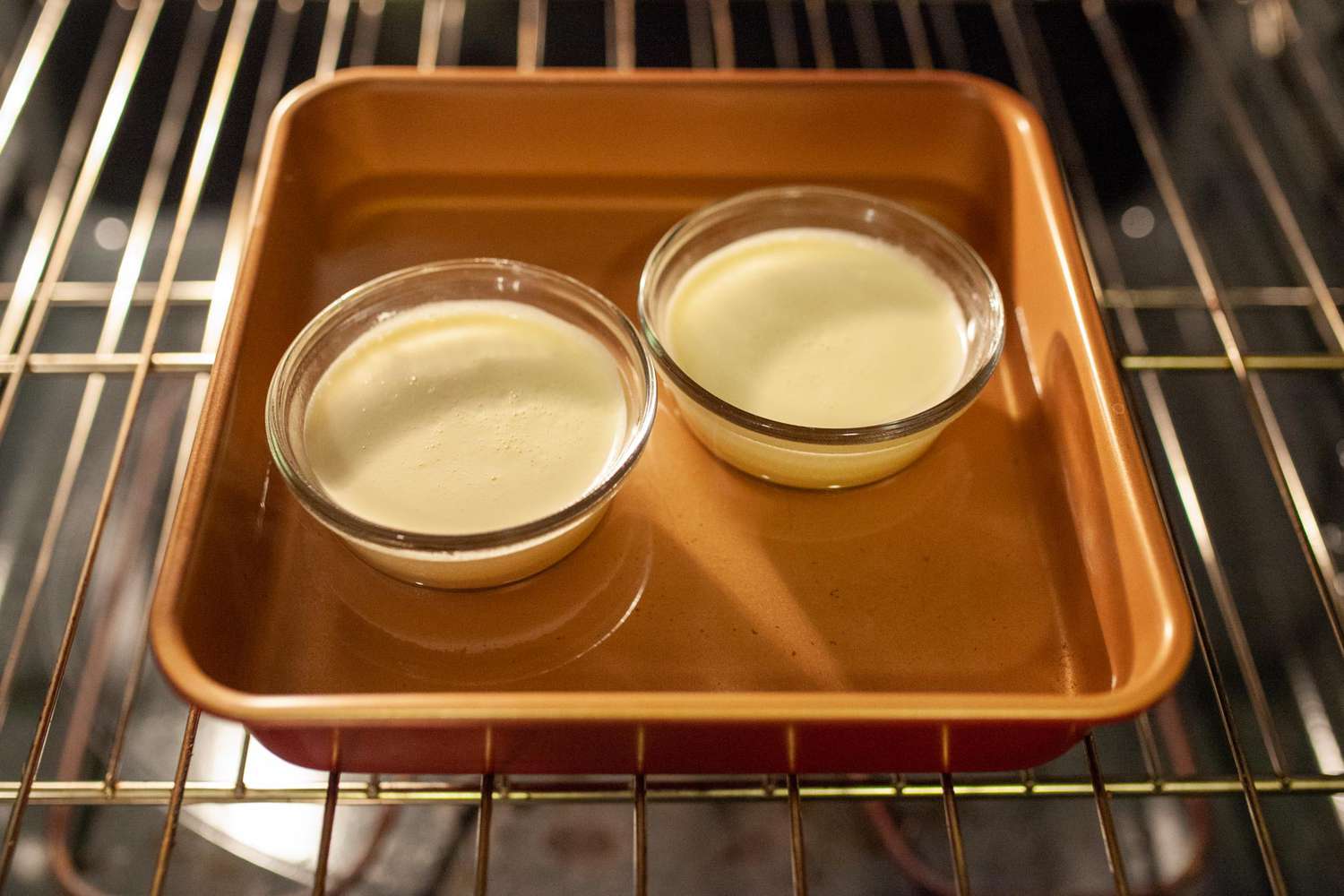 two creme brulees in a water bath in the oven