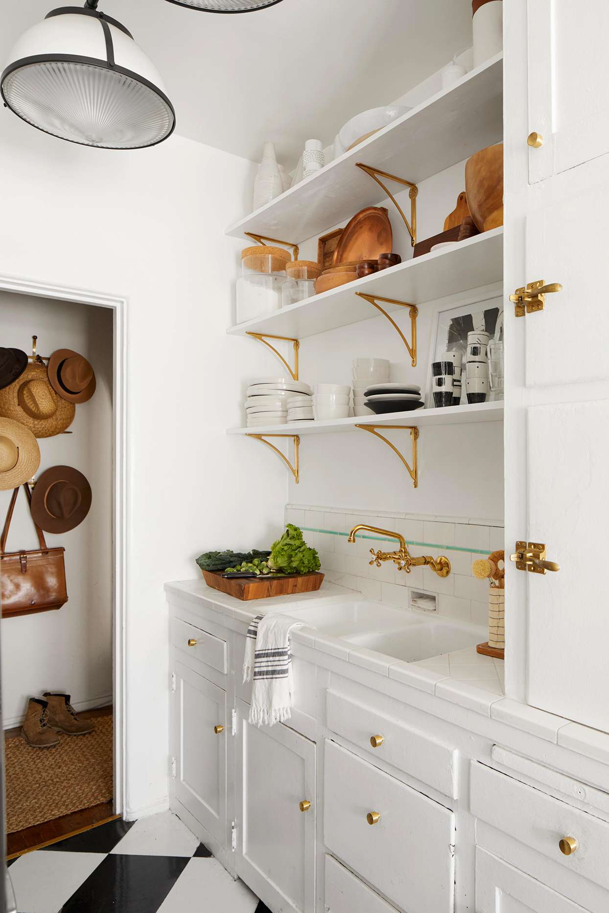 small white kitchen with open shelves on gold brackets
