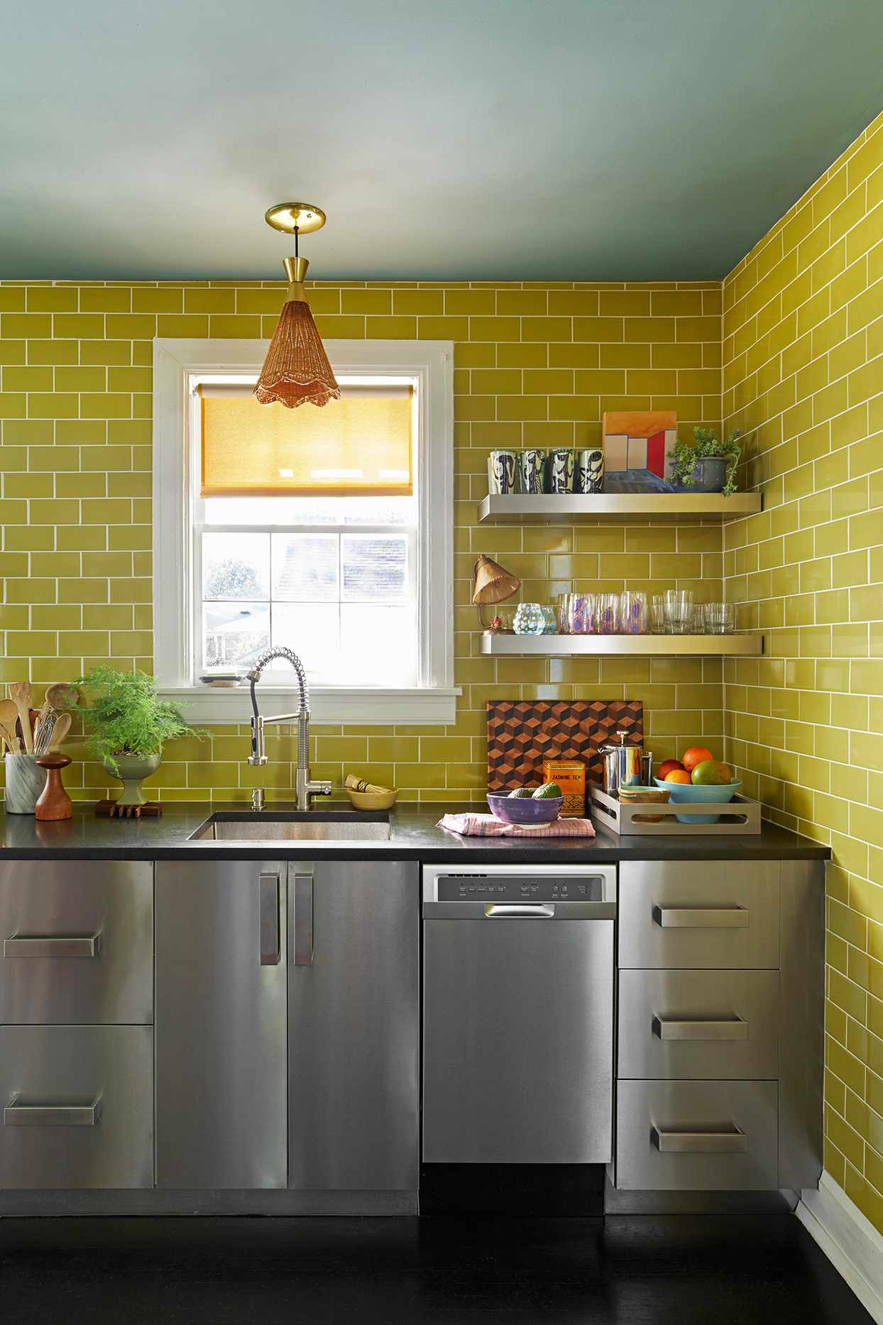 stainless steel kitchen with chartreuse subway tile on walls