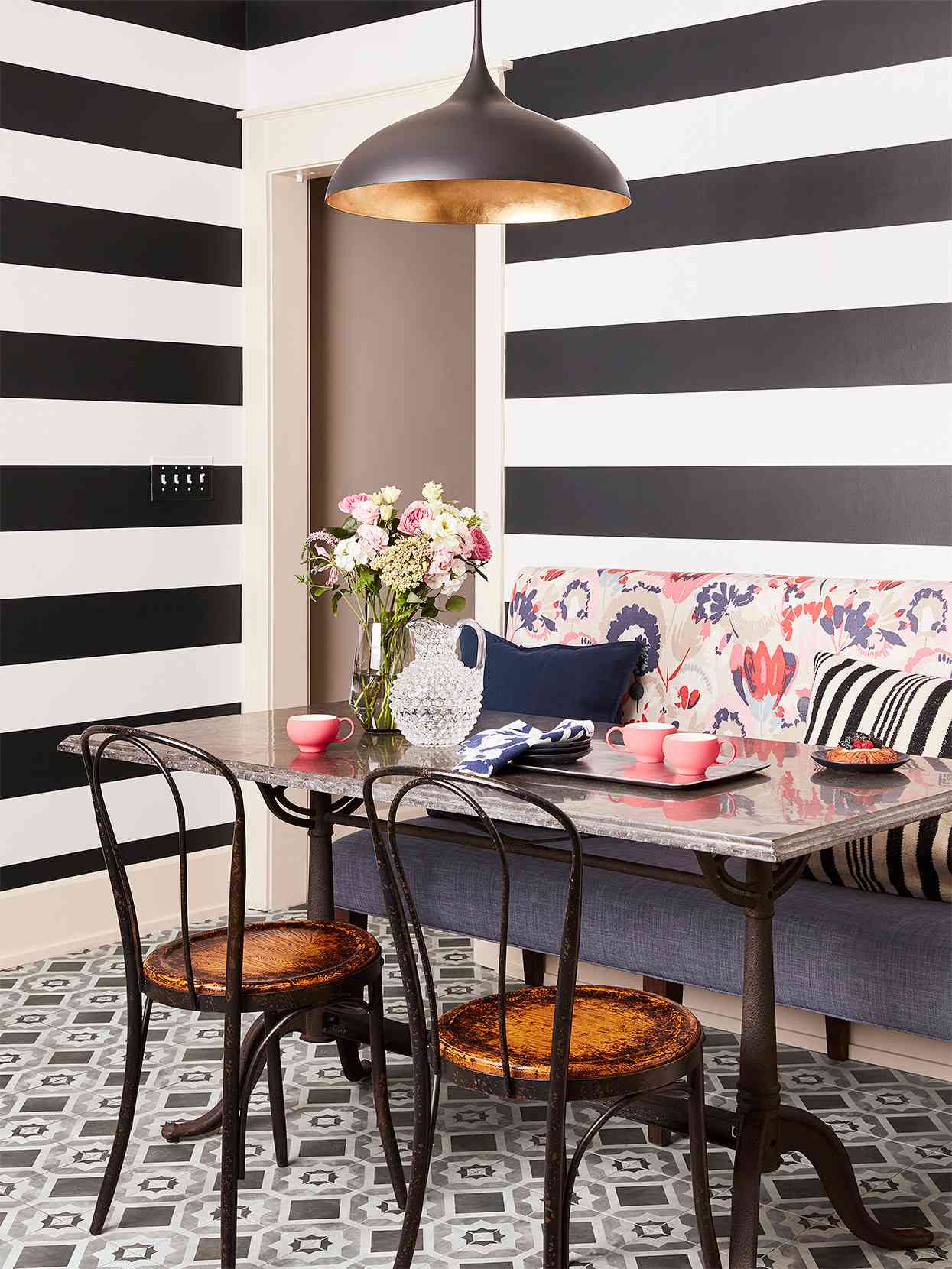 dining nook with black and white stripes on wall and floral cushion