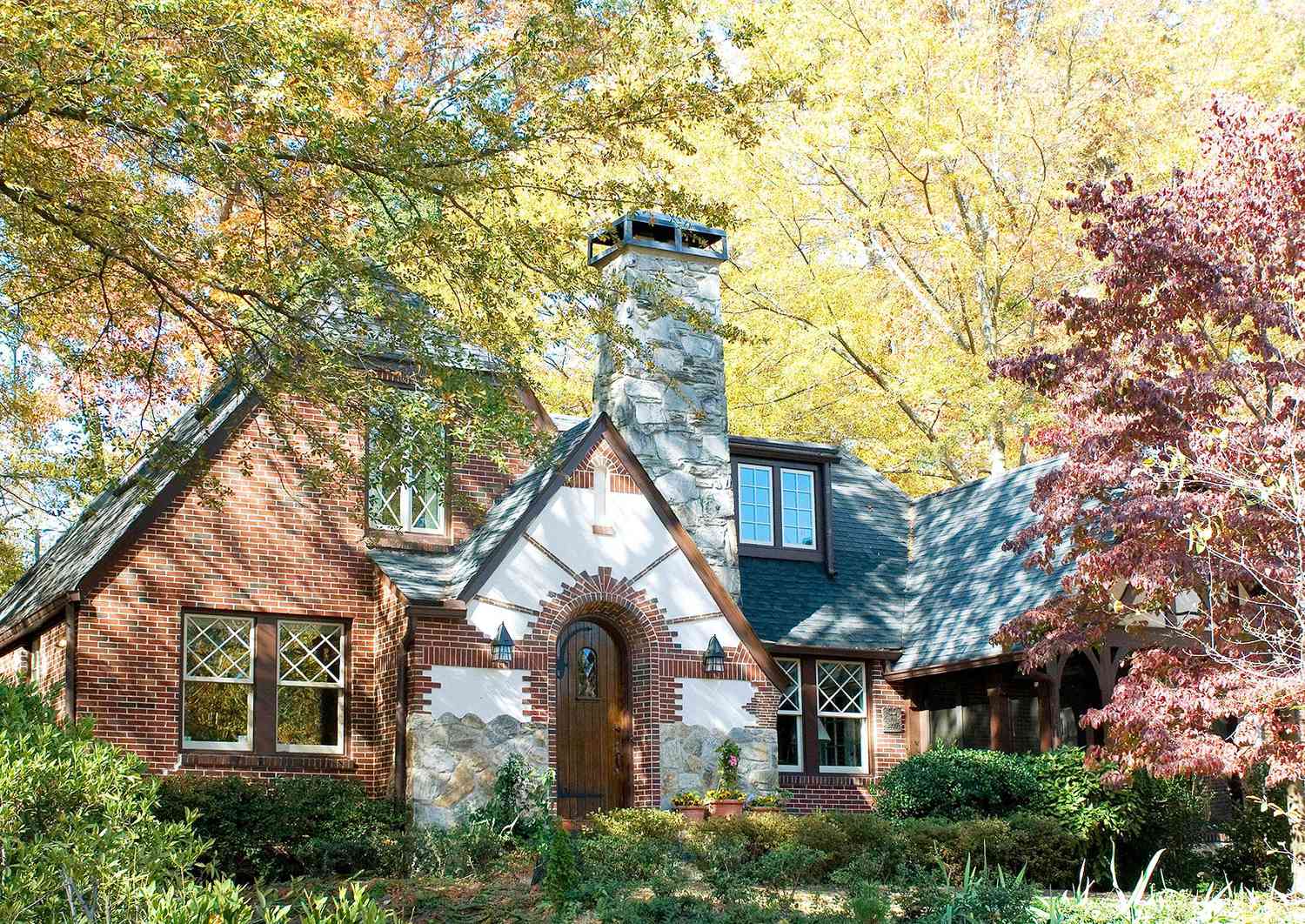 red brick tudor-inspired home with stone chimney