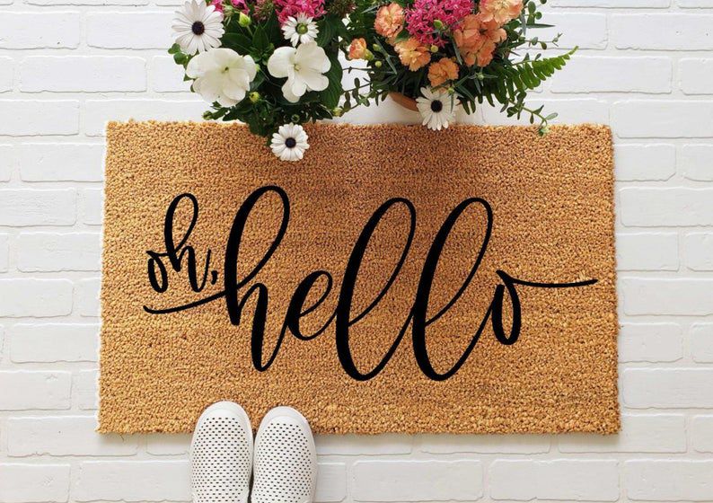 brown doormat that says 'oh hello' in black script