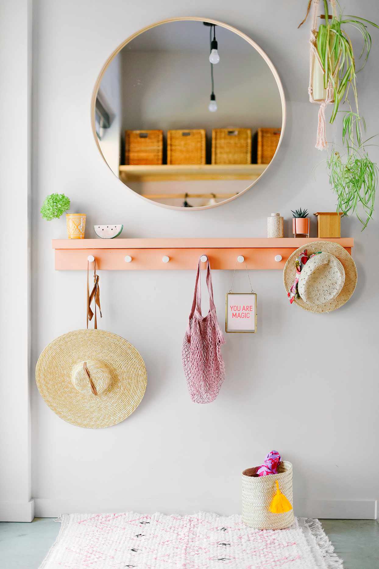 coral hanging shelf and round mirror in entryway