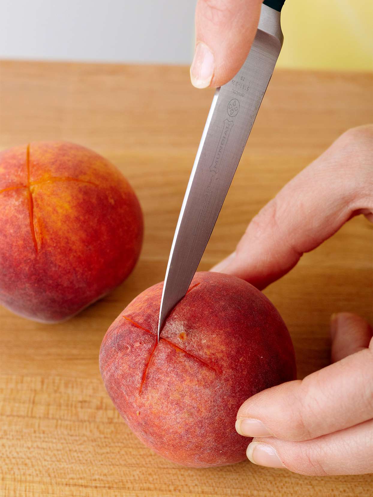 knife cutting an X into a peach