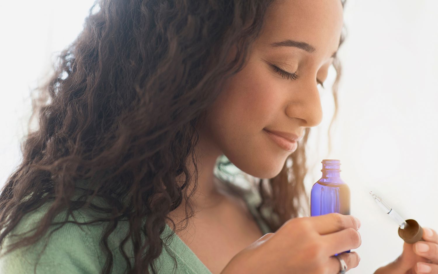 woman smelling essential oils from a bottle