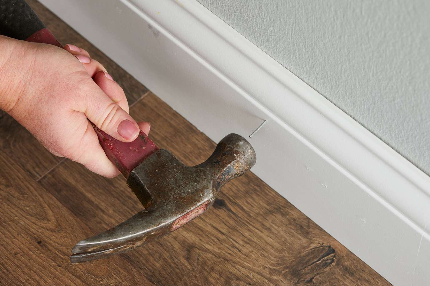 securing baseboard with hammer