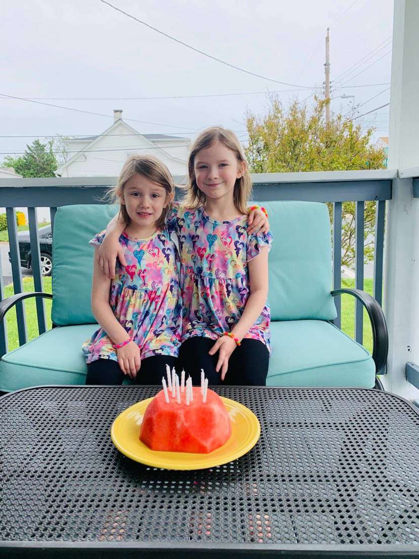 two girls posing by a cake