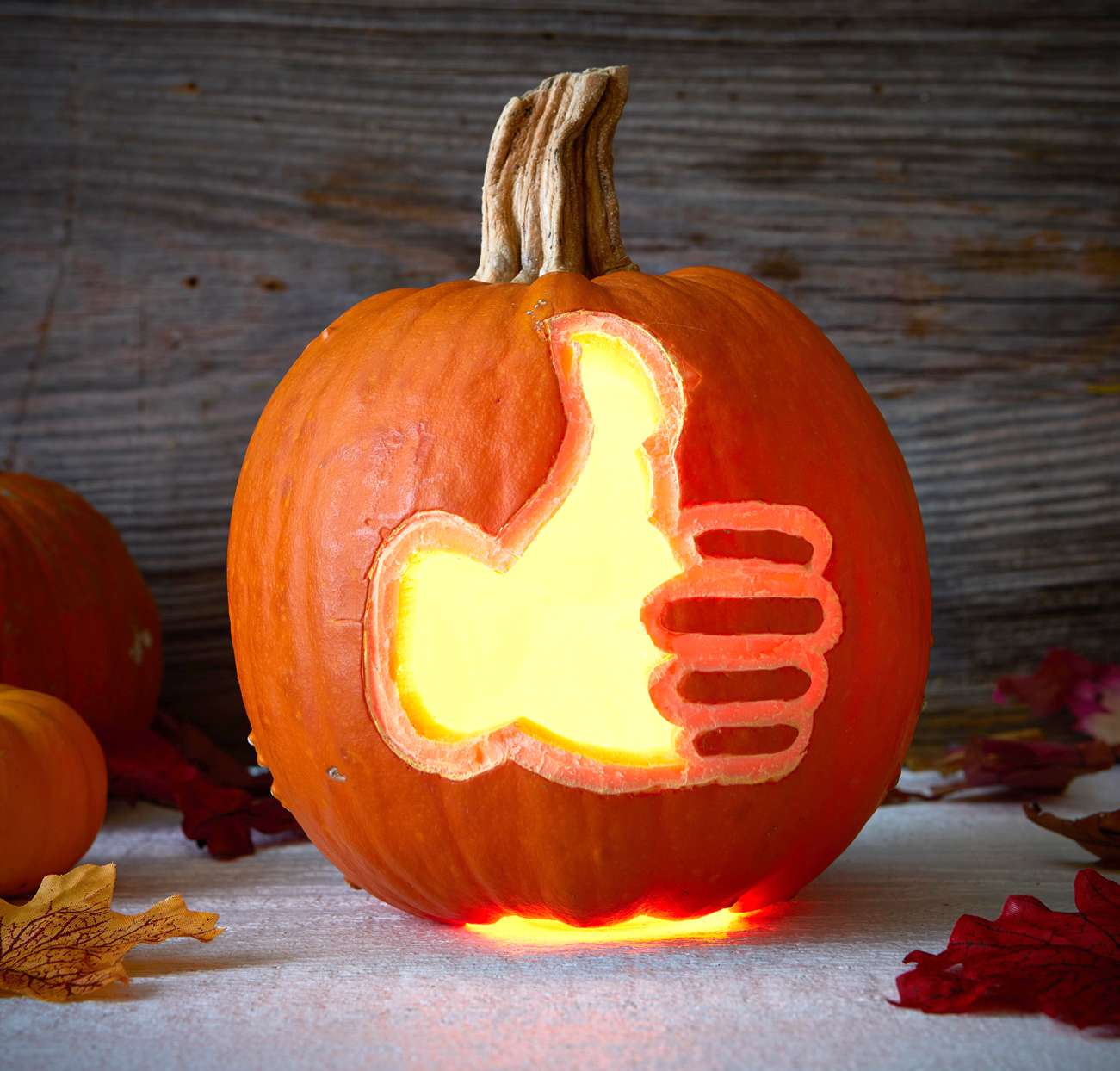 carved pumpkin thumbs up symbol lit inside
