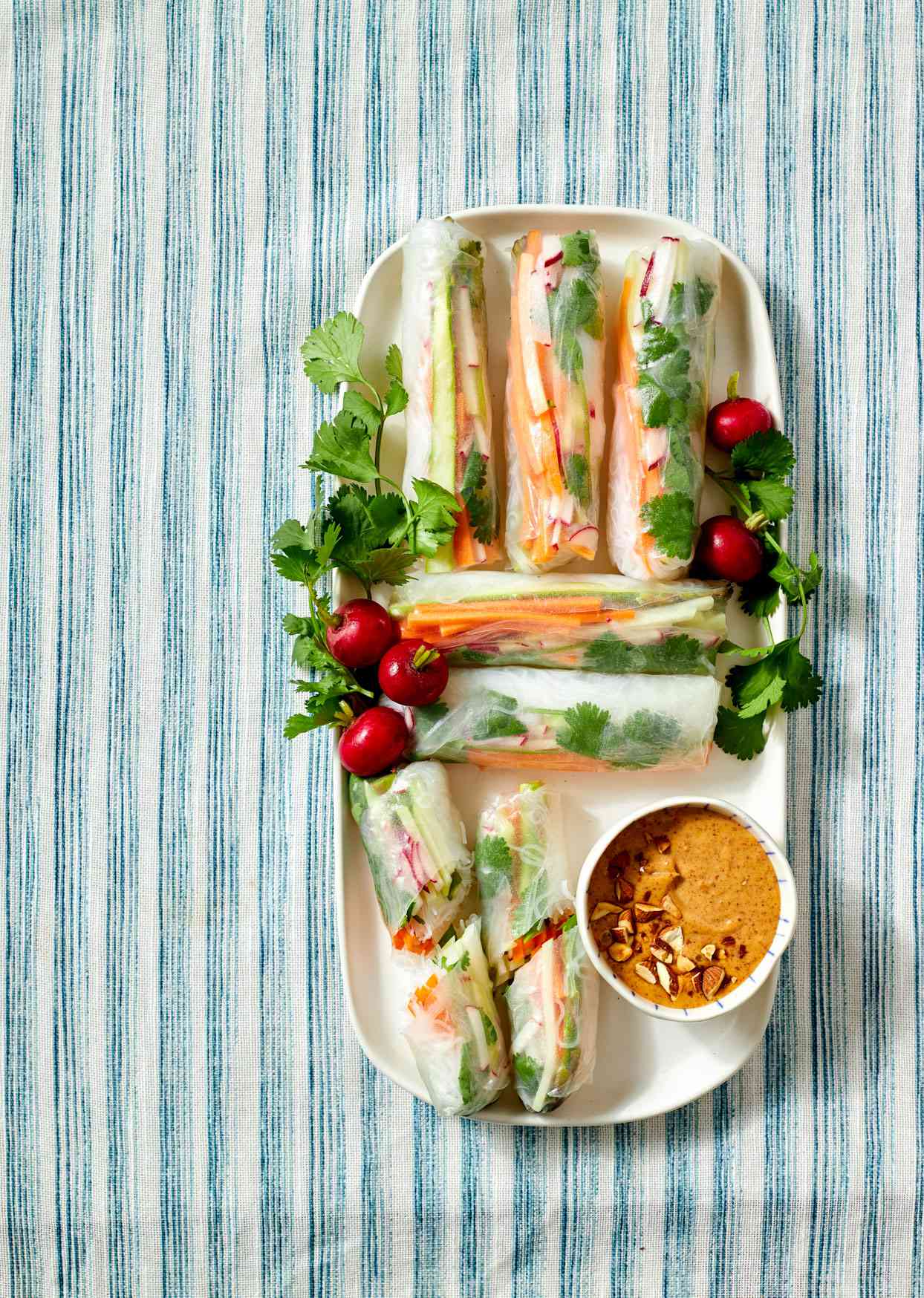 tray of veggie spring rolls with side cup of almond sauce