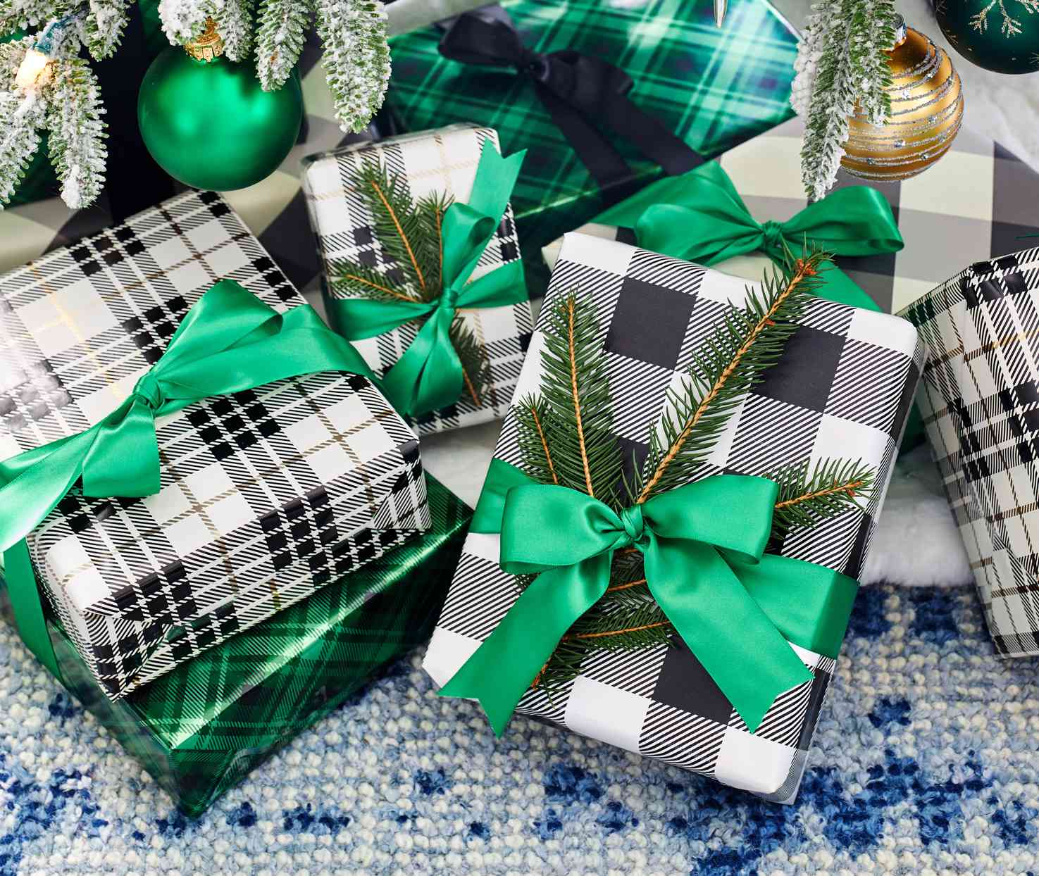 pile of gifts under holiday tree wrapped in plaid paper and green ribbons