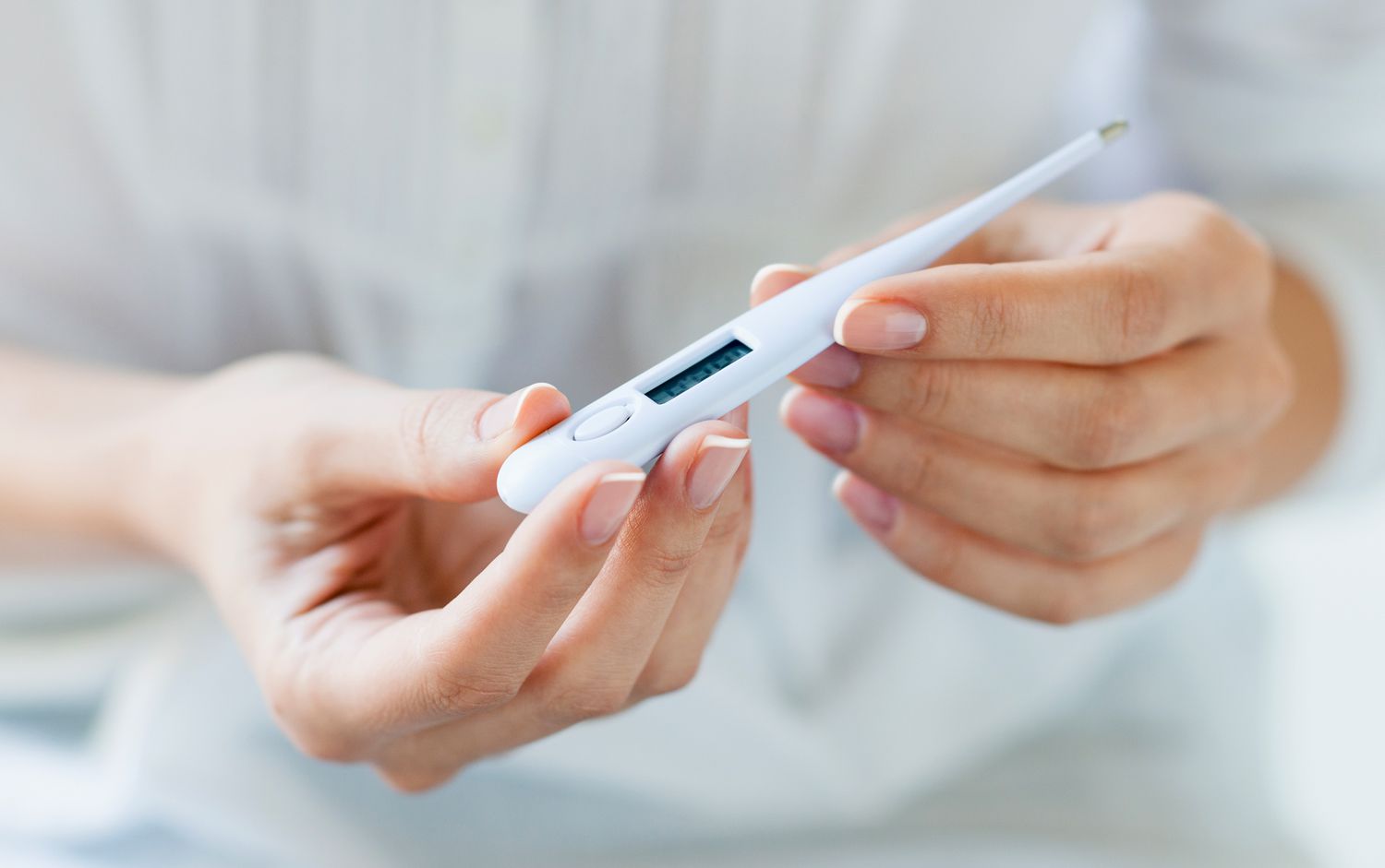 close up of woman holding a digital thermometer