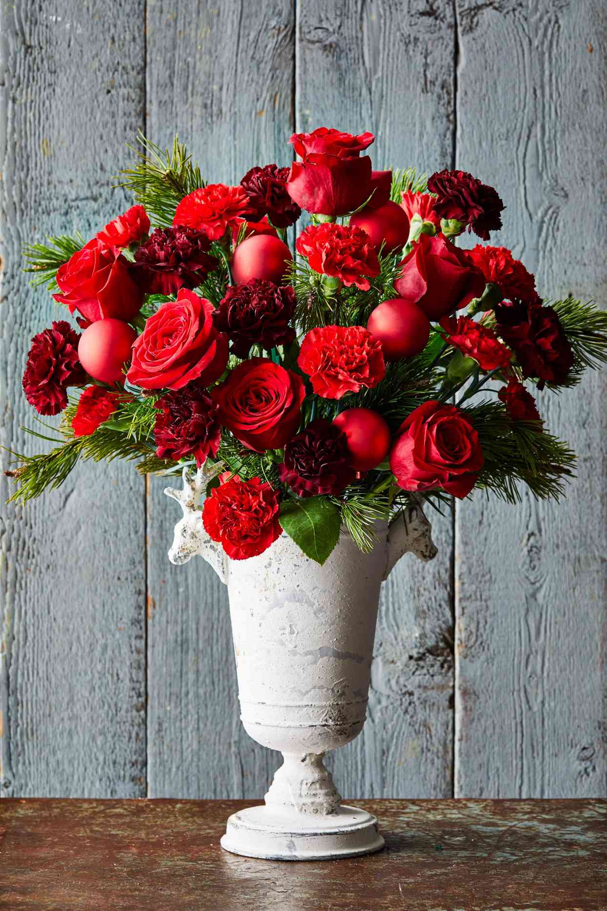 red roses and carnations in white stone vase