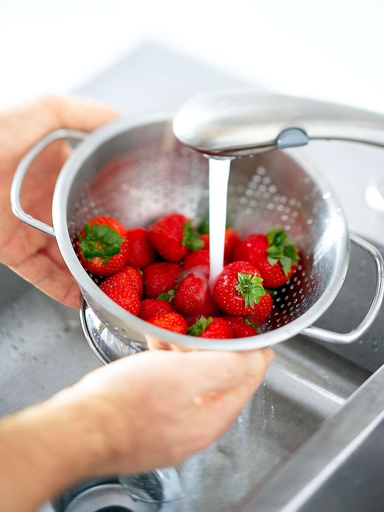 washing strawberries in colander