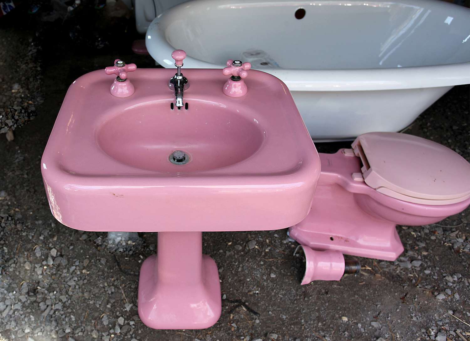 antique bubblegum pink pedestal sink and toilet bath fixtures near clawfoot tub