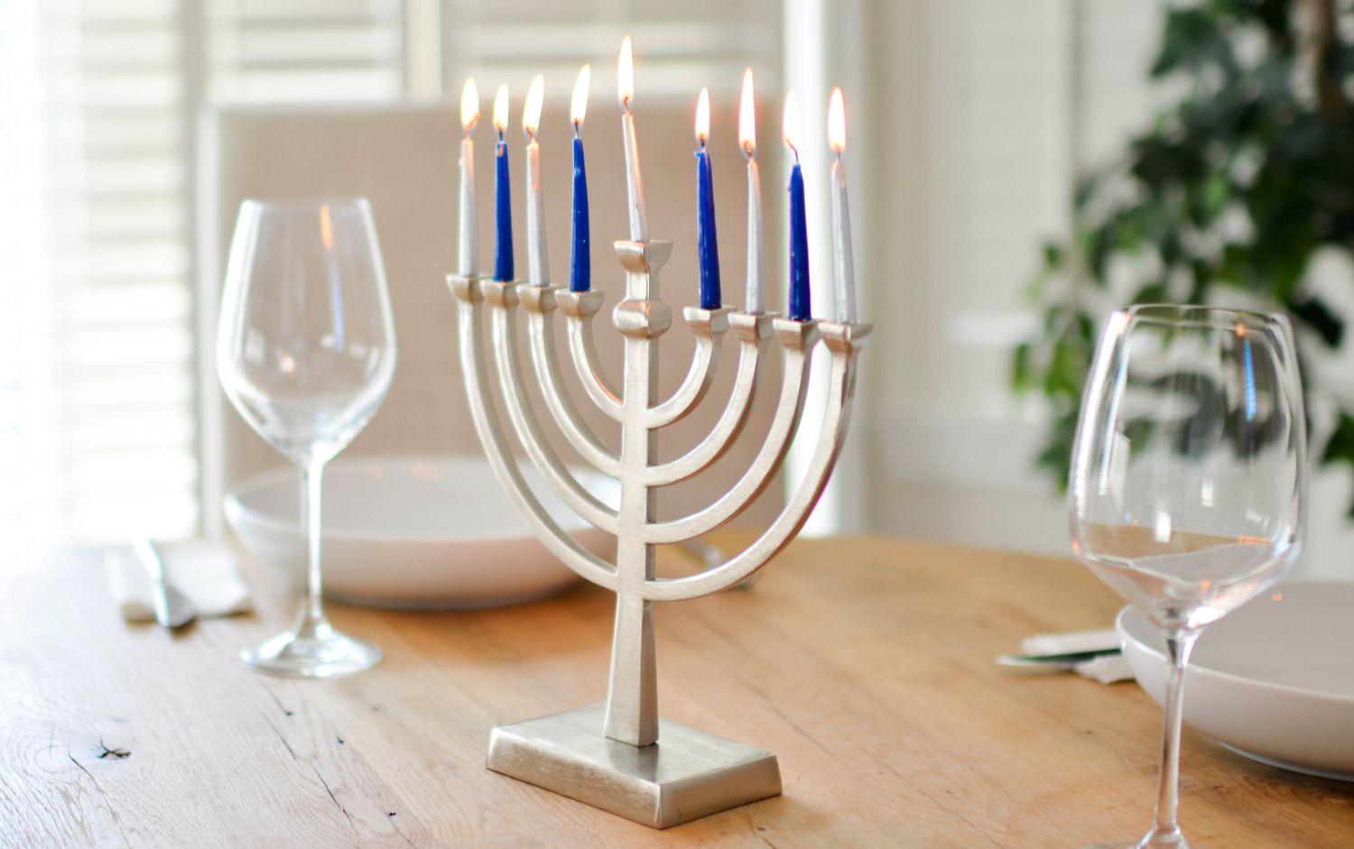 A lit menorah on a table with place settings
