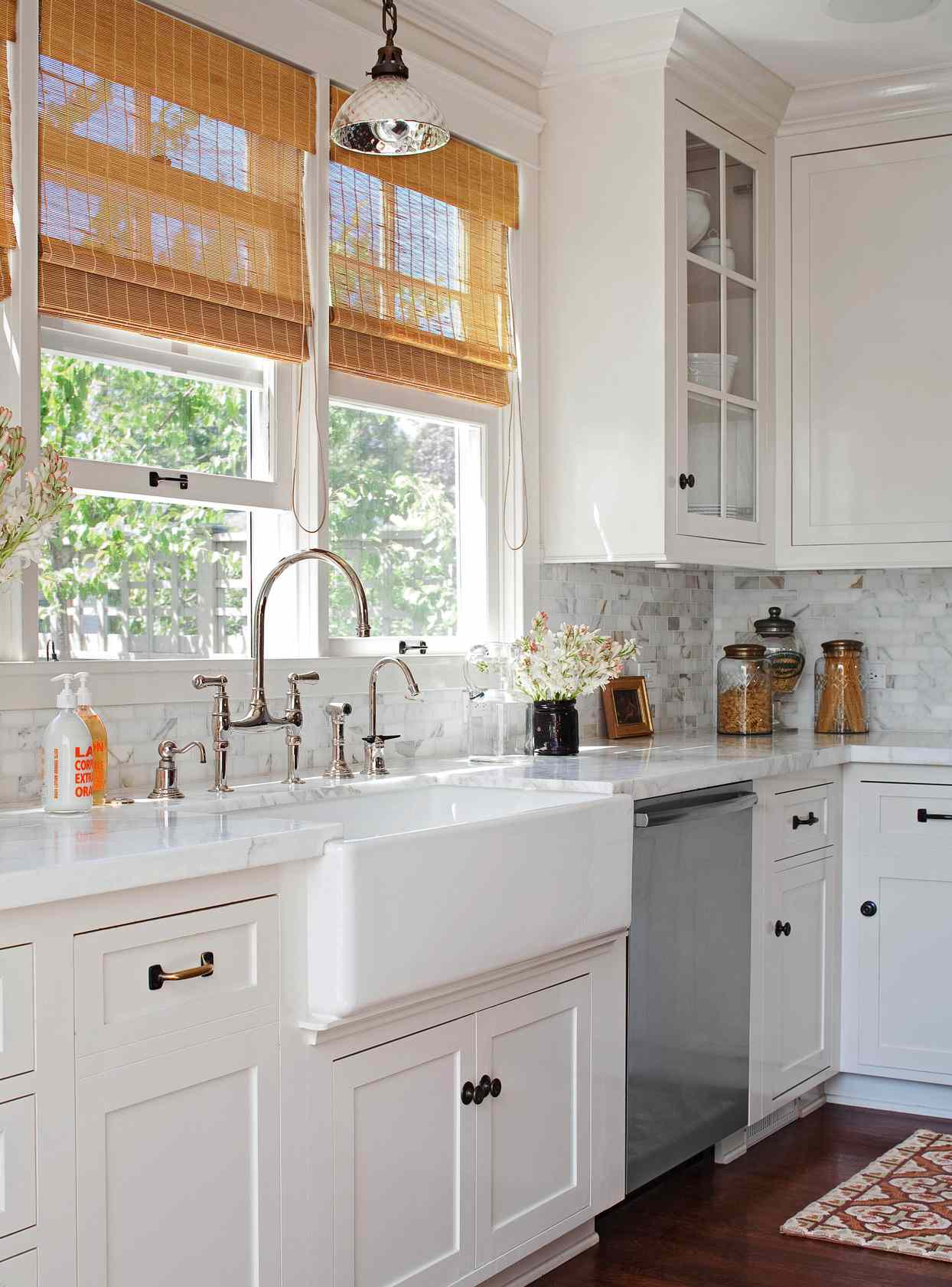 white kitchen cabinets with crystal pendant light above sink