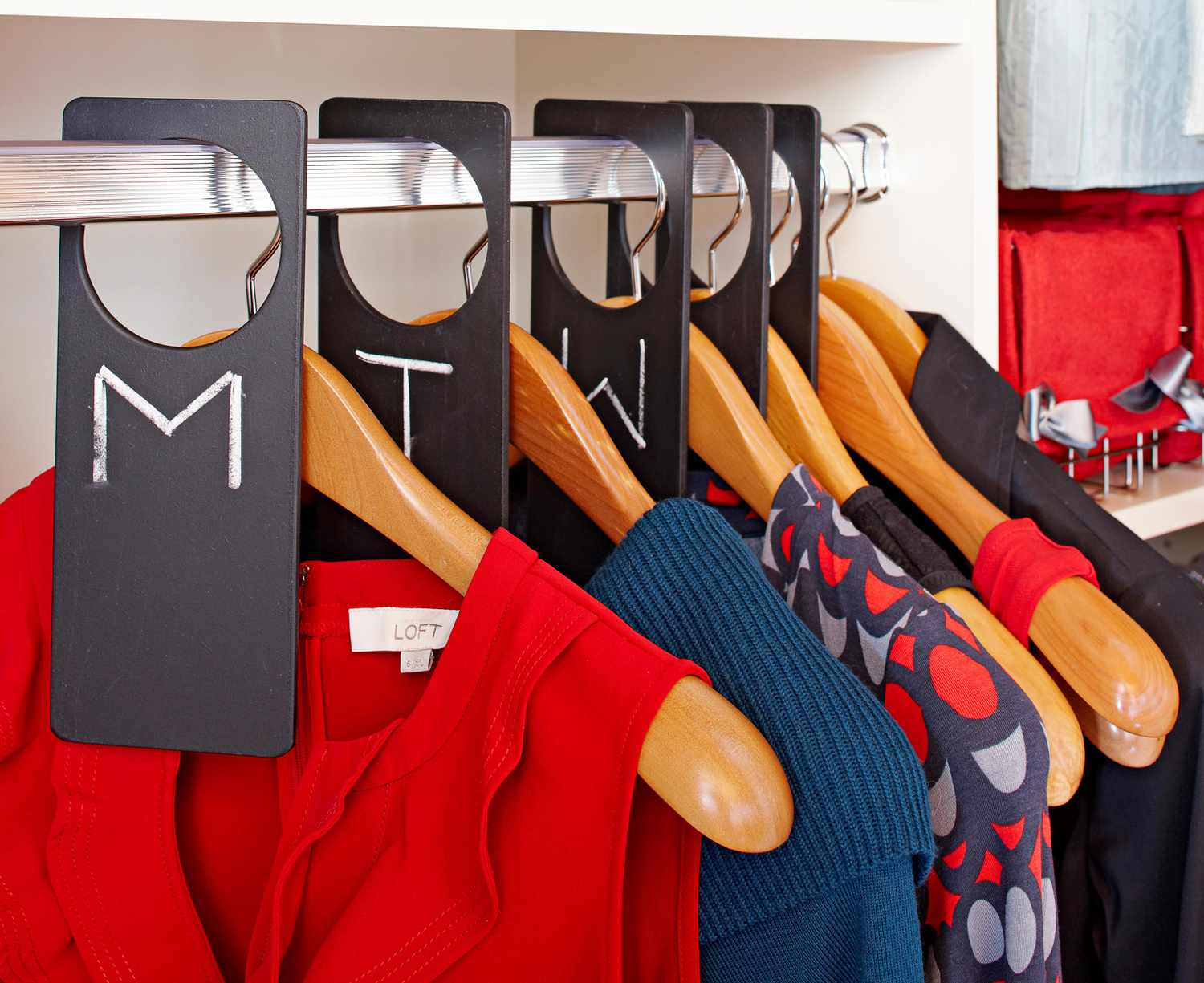 clothing hung on wooden hangers between dividers
