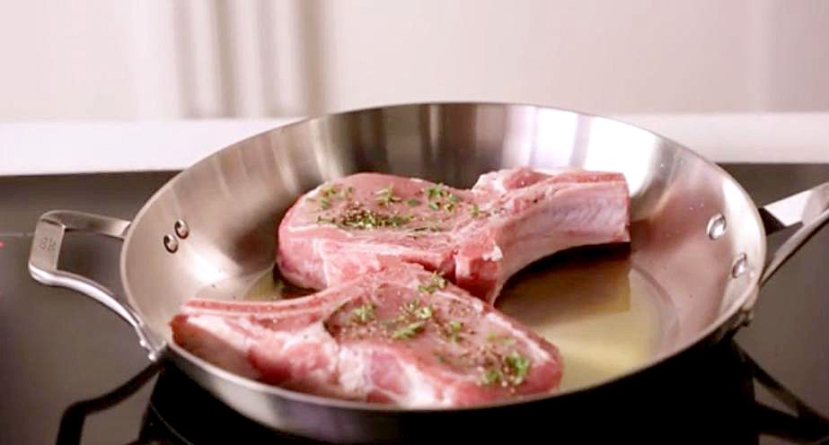 Close up of pork chops in frying pan