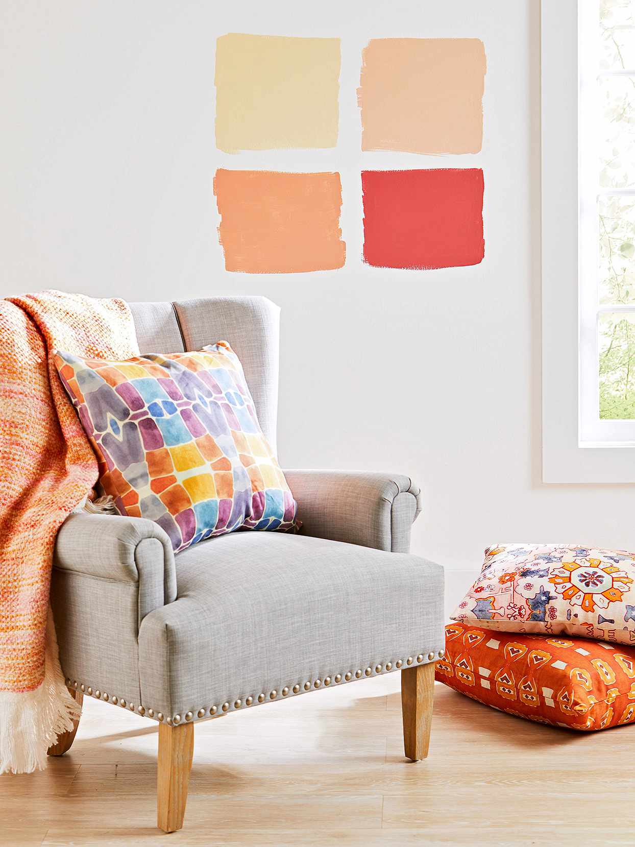 traditional armchair with bright throw pillow and throw with four warm paint swatches on wall