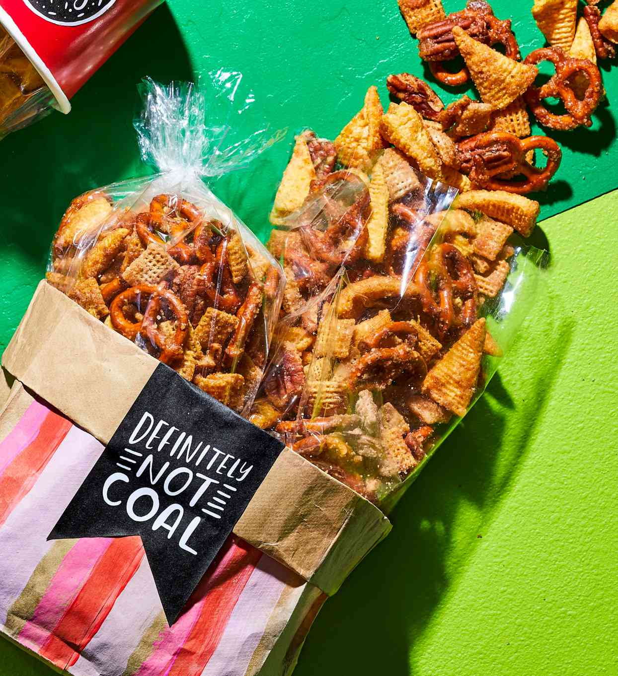 Cinnamon Churro Snack Mix spilling out of red containers on green background