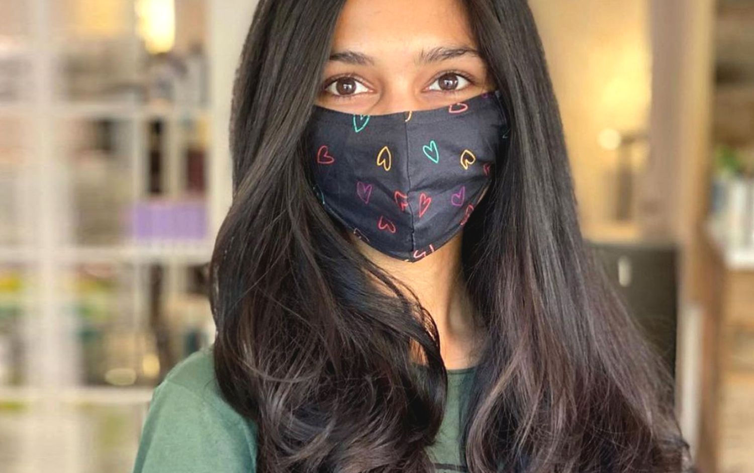 Woman with long, dark hair and a face mask