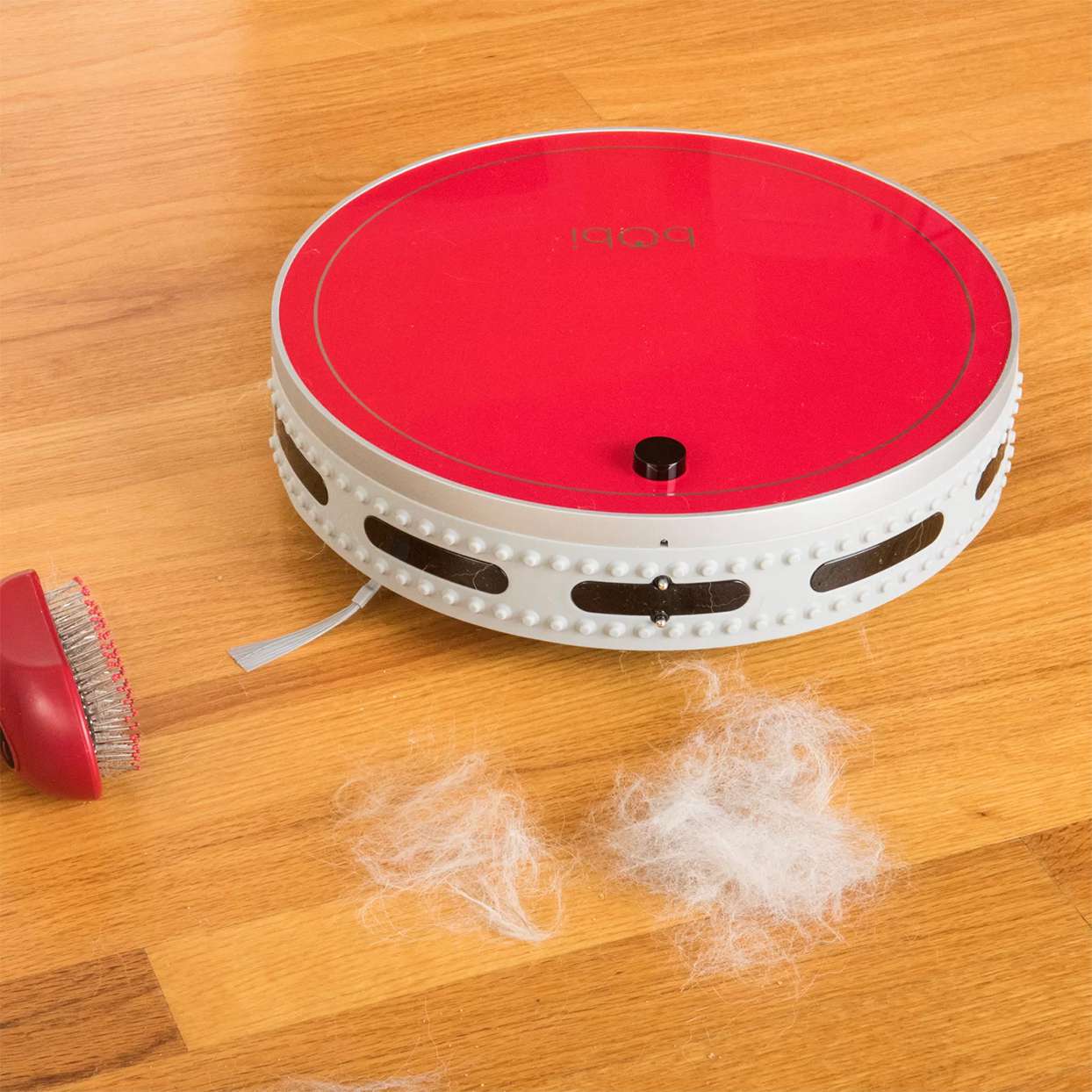 red robot vacuum on wood floor