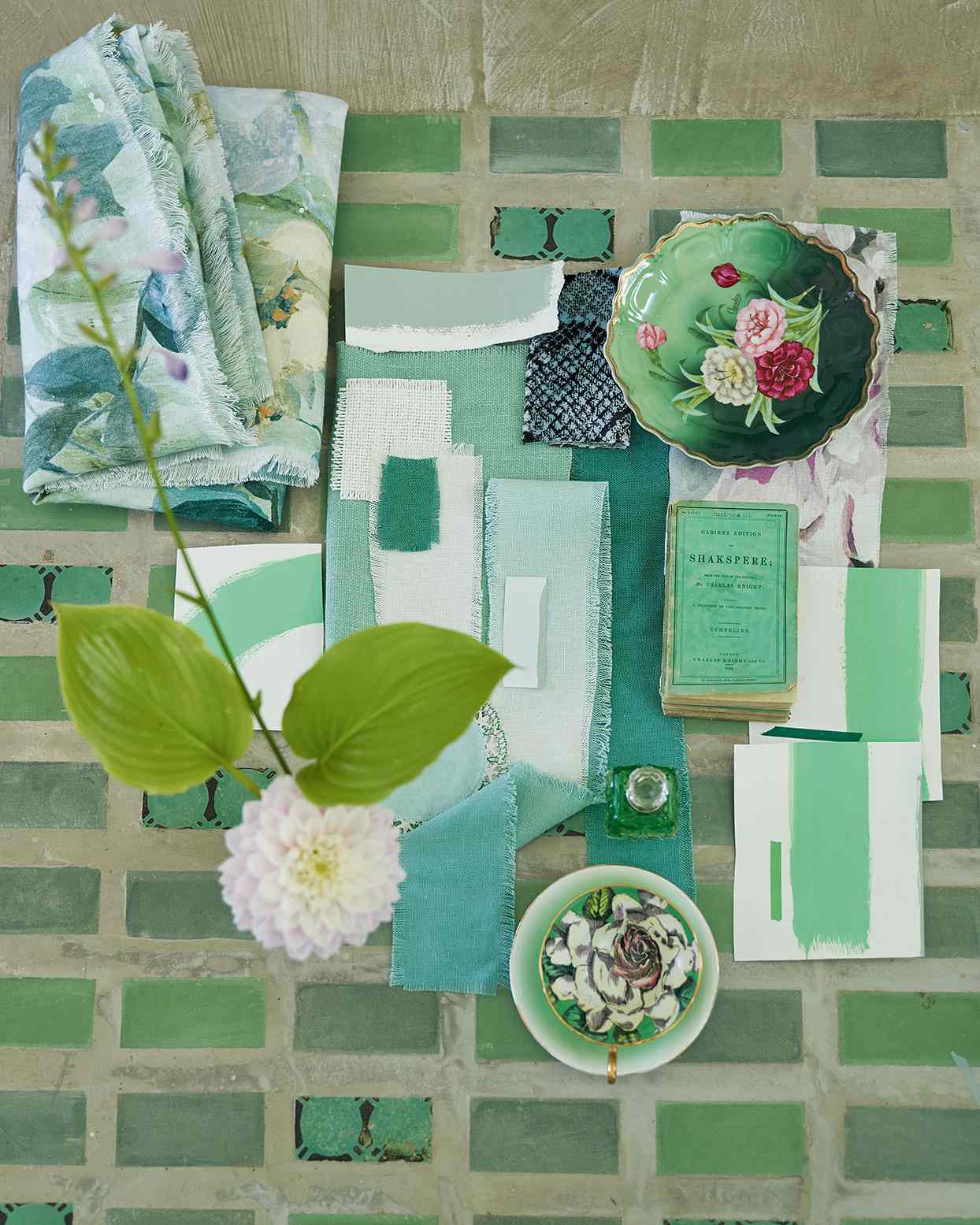 overhead shot of green mood board with dishes fabric samples and accessories