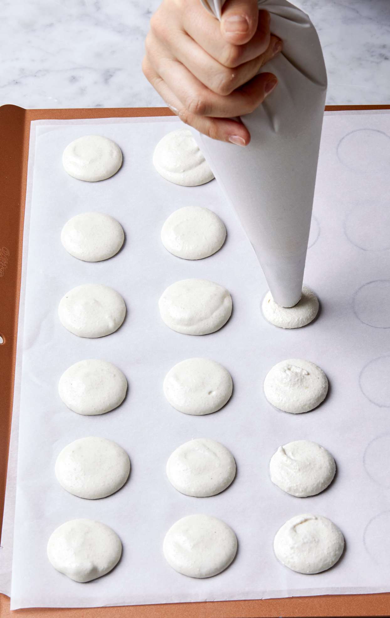 piping macarons on parchment paper