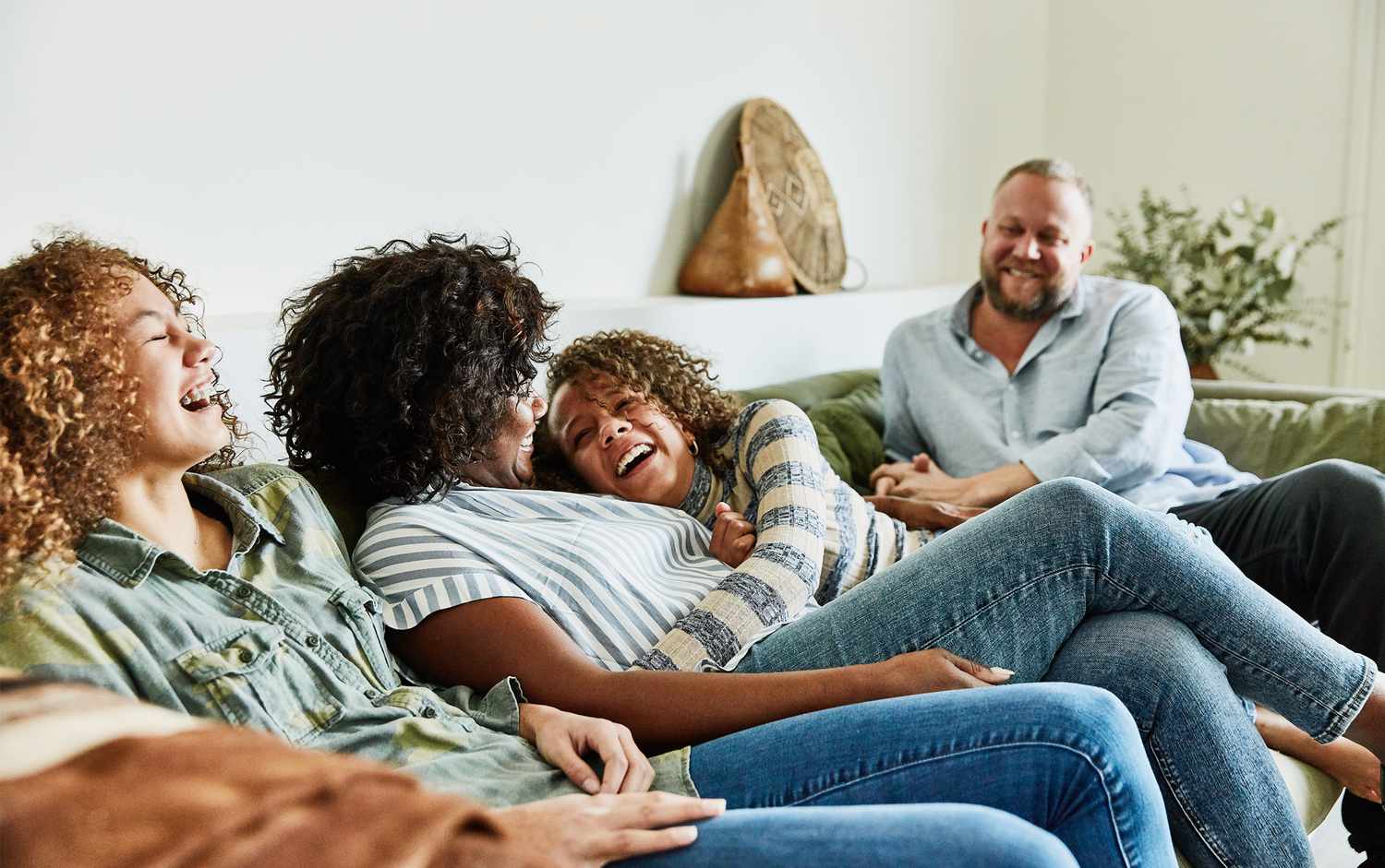 Ethnic family laughing on living room sofa