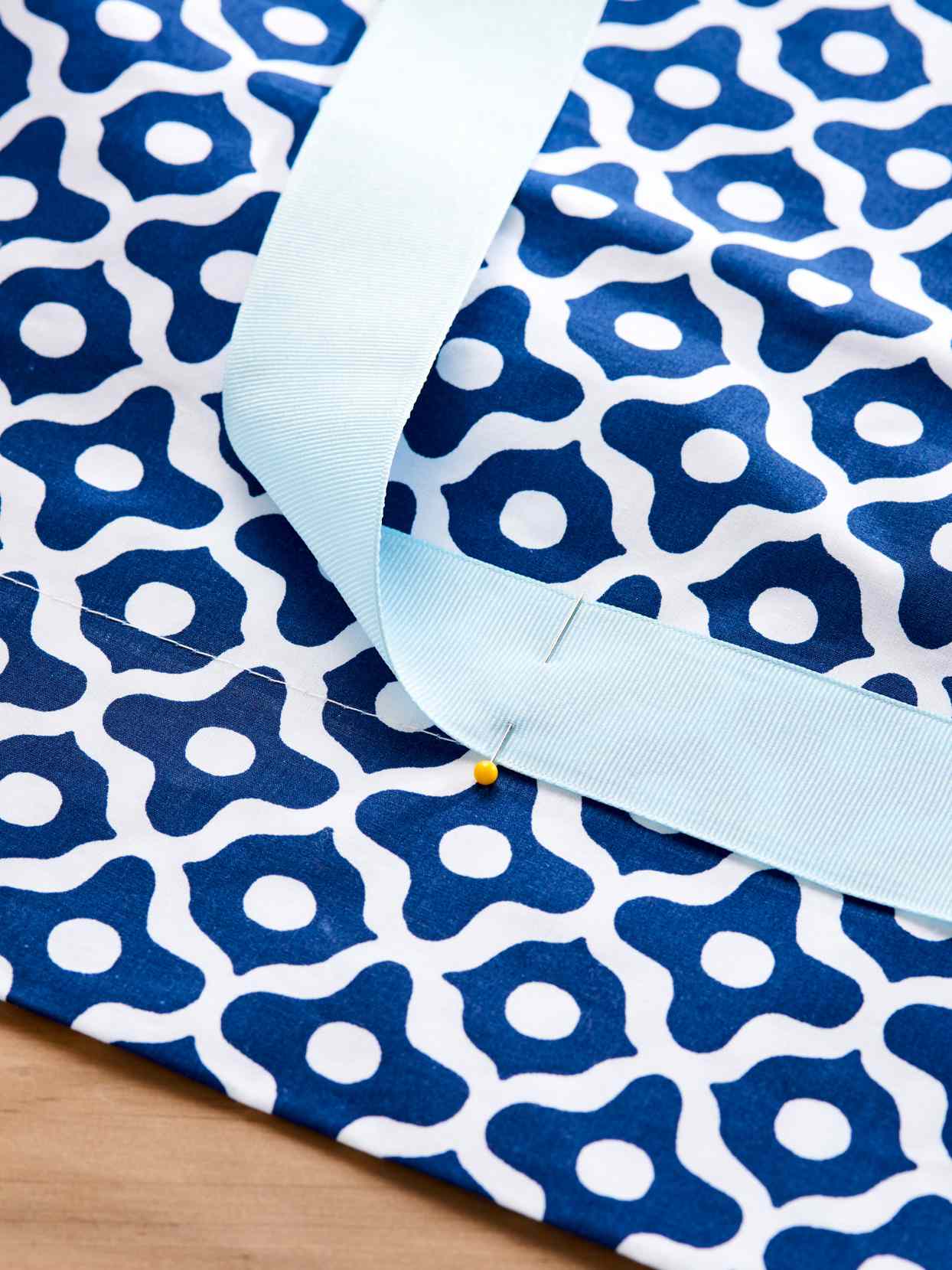 close up ribbon pinned to blue patterned bedsheet