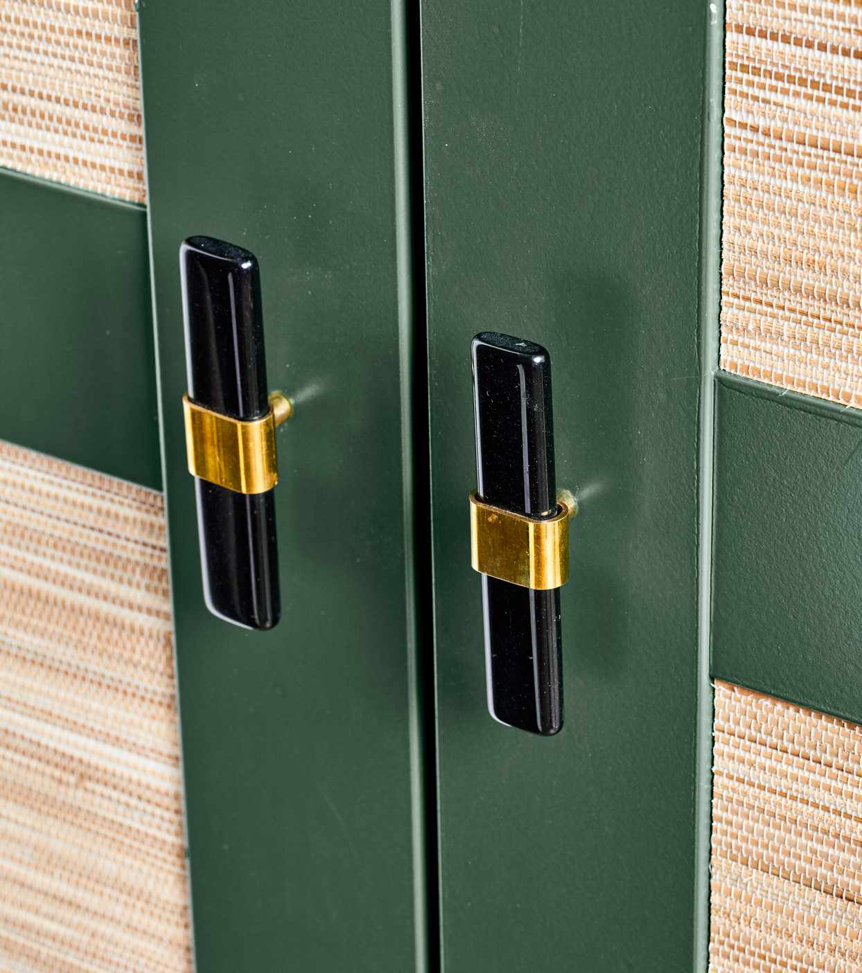close up on black handles on green cabinets