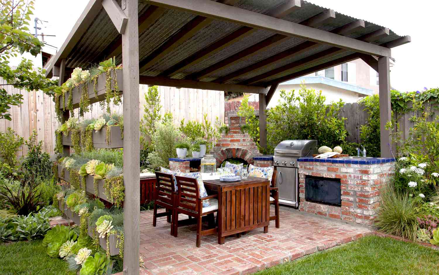 Outdoor pergola and brick kitchen with a dining table