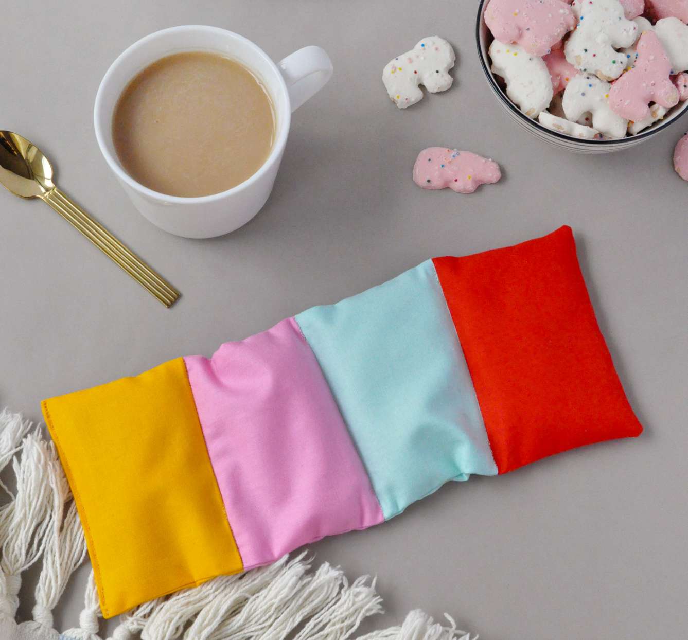 colorblock heating pad with warm cup of tea and cookies