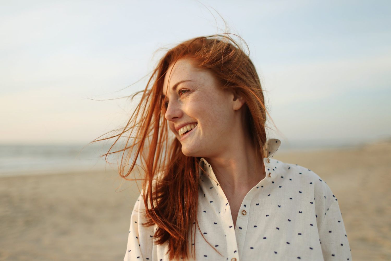 woman with red hair smiling in the sun