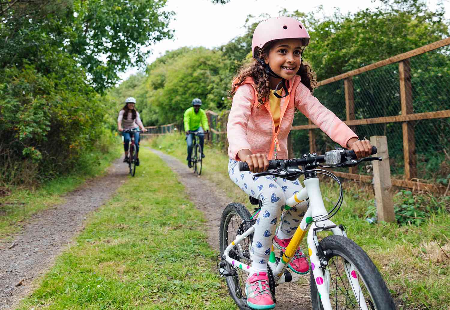 girl riding bike with family on outdoor trail