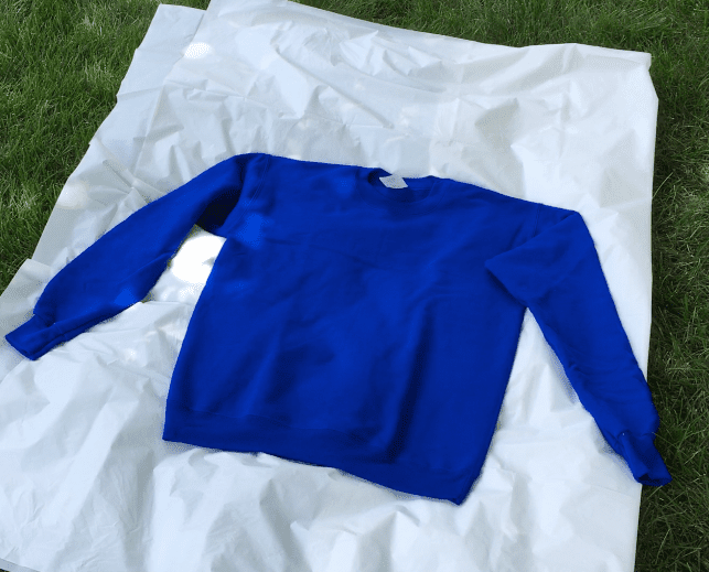 blue sweatshirt on tarp for reverse tie dye