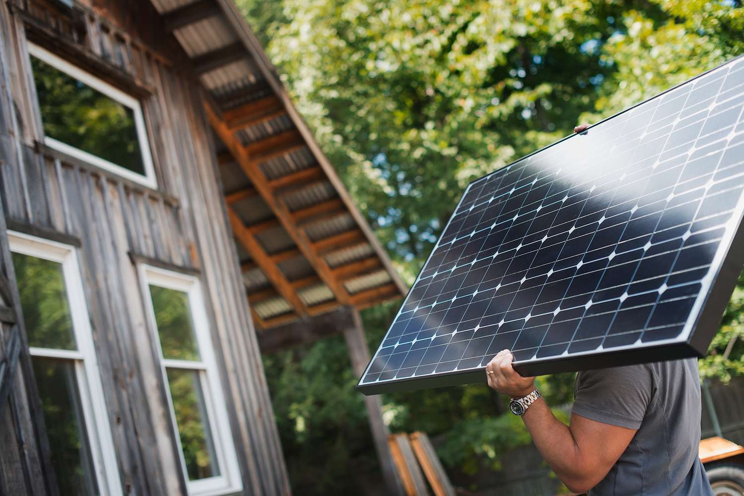 person carrying solar panels to house for installation