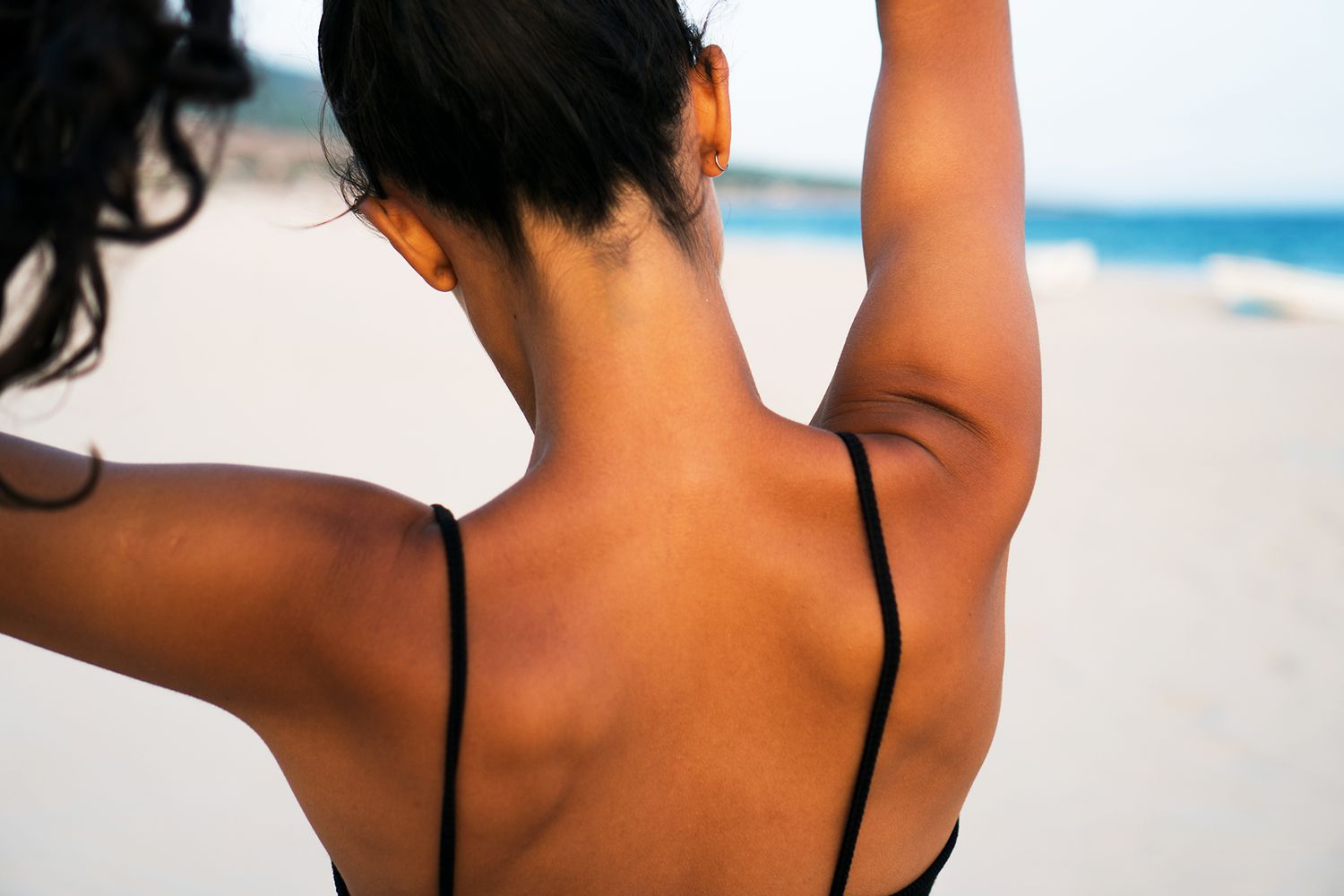 back and shoulders of a woman walking on the beach