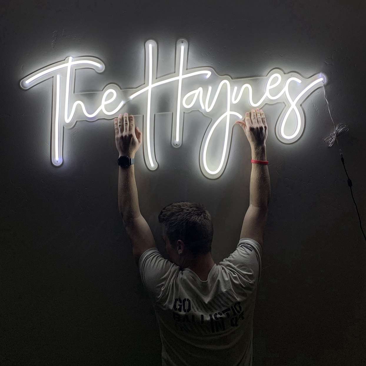 person holding up white neon sign