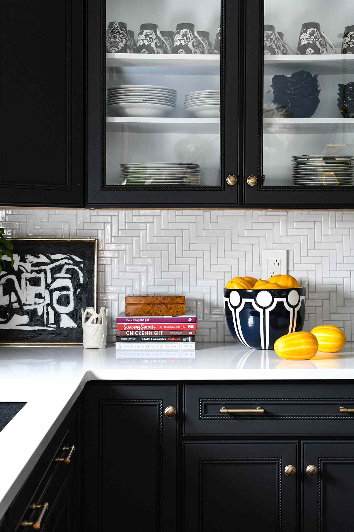 monochromatic herringbone white tile backsplash black open cabinets