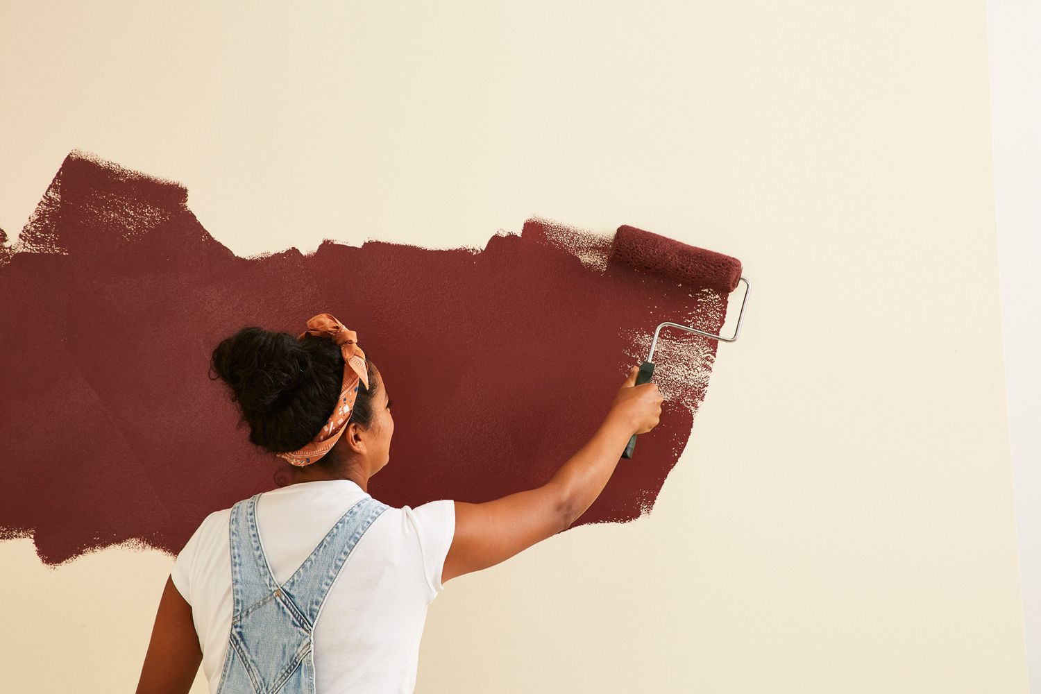 using roller to paint wall with brown paint